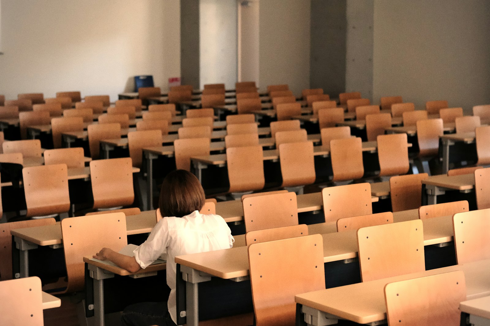 広い教室で、いちばん前の席にひとりで座っている生徒の後ろ姿